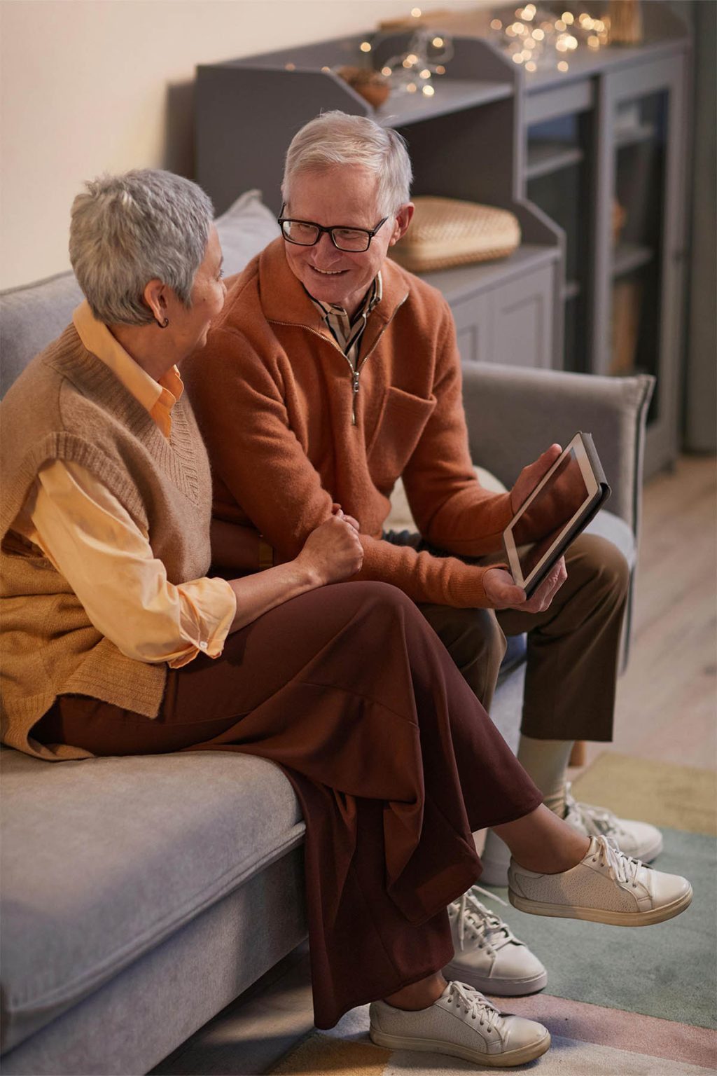 Two retirees, an older couple, sit on a sofa discussing FPFoCo financial plans